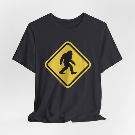 Yellow warning sign graphic of a Sasquatch crossing on a black t-shirt.
