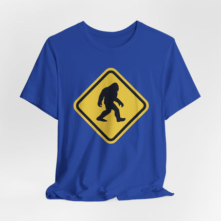 Bigfoot Sasquatch crossing warning sign graphic on a blue t-shirt.