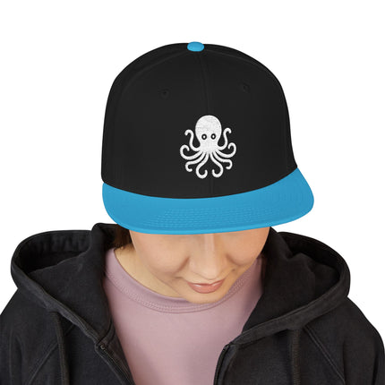 Black snapback cap with white embroidered octopus design and contrasting blue brim.