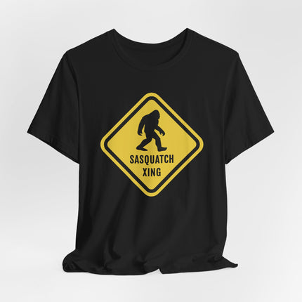 Yellow Sasquatch crossing caution sign graphic on a black t-shirt. Bigfoot cryptozoology tee.