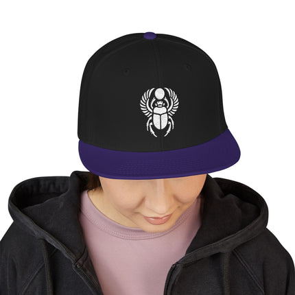 Black snapback cap with embroidered Egyptian scarab beetle design.
