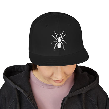 Black snapback cap with white embroidered tarantula spider graphic.