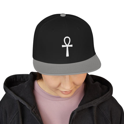 Black snapback hat featuring a white embroidered Ankh symbol. Egyptian symbol of life accessory.