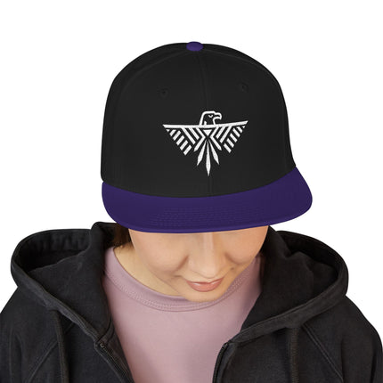 Black snapback hat with geometric thunderbird embroidery and purple brim.