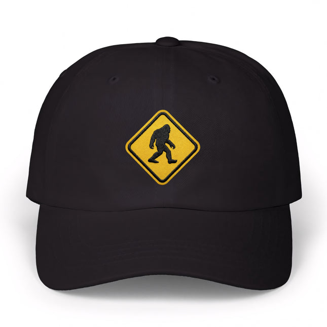 Black baseball cap featuring a yellow embroidered Bigfoot crossing warning sign.
