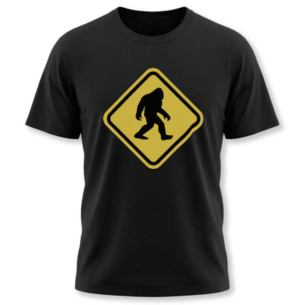 Yellow warning sign graphic of a Bigfoot Sasquatch crossing silhouette on a black t-shirt.