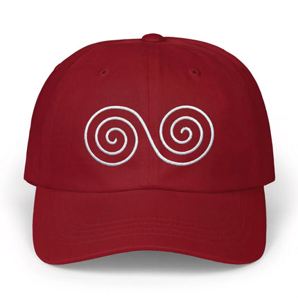Red baseball cap featuring a white embroidered double spiral Celtic symbol.