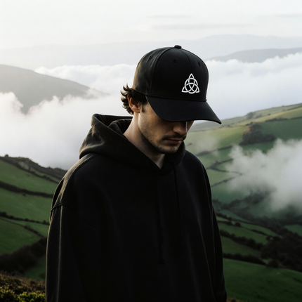Black baseball cap with white embroidered Celtic Triquetra knotwork symbol.