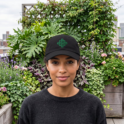 Black baseball cap with green embroidered Celtic cross knot design.