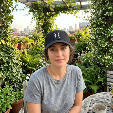 Black baseball cap featuring the embroidered Pisces zodiac symbol.