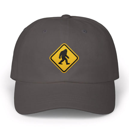 Embroidered Bigfoot warning sign cap on a dark gray baseball hat.