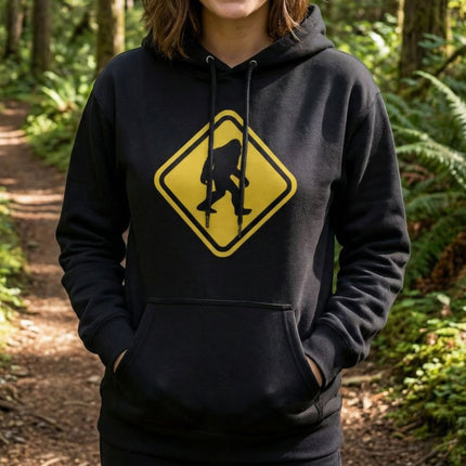 Black hoodie featuring a yellow warning sign graphic of a Bigfoot or Sasquatch silhouette.