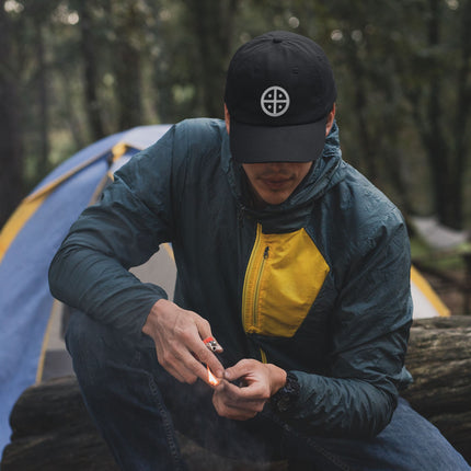 Black baseball cap featuring embroidered solar cross symbol. Ancient cosmic design for streetwear.