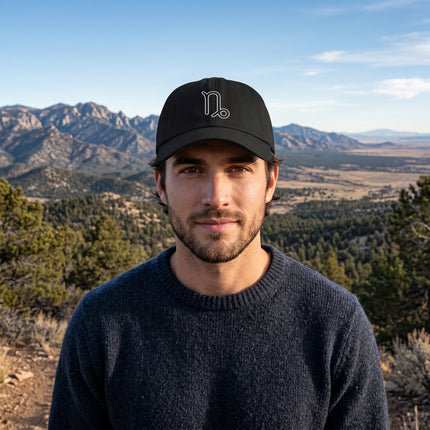 Black baseball cap featuring a minimalist embroidered Capricorn zodiac symbol.