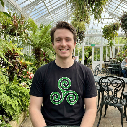 Black t-shirt featuring a vibrant green Celtic triskelion triple spiral design.