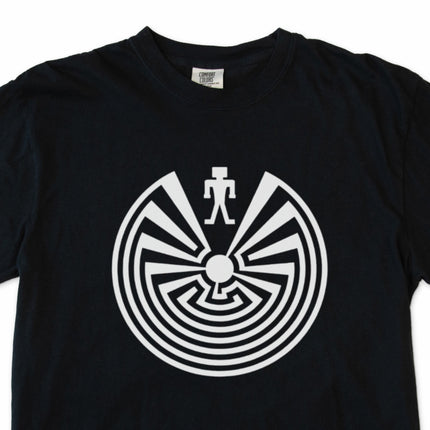 I'itoi Man In The Maze tribal symbol graphic on a black comfort colors t-shirt.