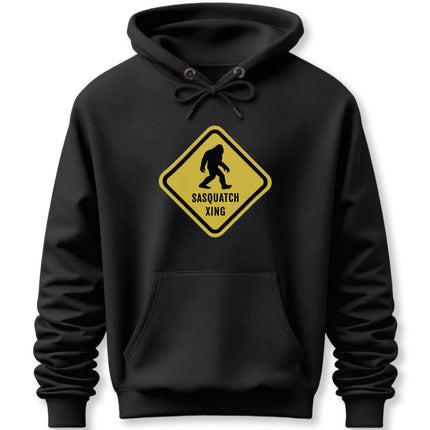 Yellow Sasquatch crossing warning sign graphic on a black pullover hoodie.